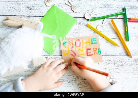 3 marzo 2024: Bambini che fanno decorazioni pasquali, scrittura a mano con matite colorate: Buona Pasqua *** Kind beim Basteln von Osterdekoration, Hand schreibt mit Buntstiften: Frohe Ostern Foto Stock