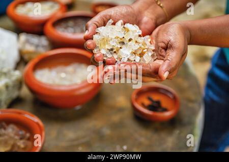 Donna tiene in mano pietre preziose lavate, sul tavolo ci sono molte ciotole con pietre preziose. Sri Lanka, Meetiyagoda. Foto Stock