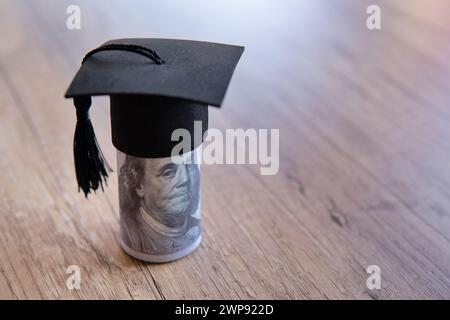 Immagine ravvicinata del cappello di graduazione e dei soldi sul tavolo. Borsa di studio, concetto di tasse educative. Copia spazio per il testo. Foto Stock