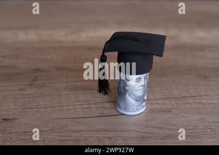 Immagine ravvicinata del cappello di graduazione e dei soldi sul tavolo. Borsa di studio, concetto di tasse educative. Copia spazio per il testo. Foto Stock