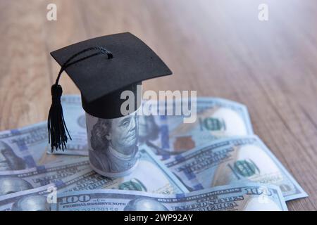 Immagine ravvicinata del cappello di graduazione e dei soldi sul tavolo. Borsa di studio, concetto di tasse educative. Copia spazio per il testo. Foto Stock