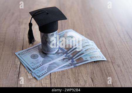 Immagine ravvicinata del cappello di graduazione e dei soldi sul tavolo. Borsa di studio, concetto di tasse educative. Copia spazio per il testo. Foto Stock