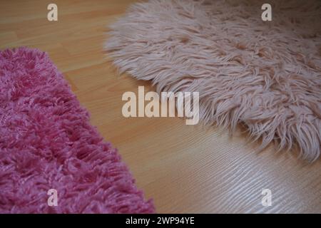 Tappeto lungo in pelo rosa su un pavimento in laminato beige. Interno femminile per una stanza o una camera da letto di una ragazza o di una donna. Design degli interni in tonalità rosa. Pavimento i Foto Stock