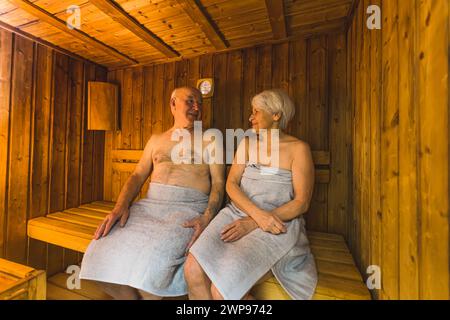 una coppia di anziani seduto nella sauna di legno e si diverte benissimo, con un tocco medio pieno, concetto per anziani. Foto di alta qualità Foto Stock