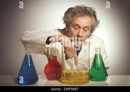 Un vecchio pazzo chimico che prepara un esperimento chimico con alcuni liquidi Foto Stock