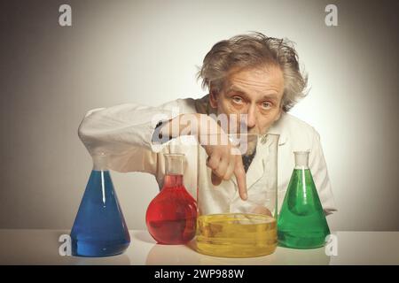 Un vecchio pazzo chimico che prepara un esperimento chimico con alcuni liquidi Foto Stock