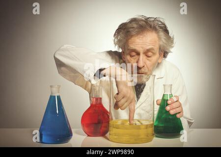 Un vecchio pazzo chimico che prepara un esperimento chimico con alcuni liquidi Foto Stock