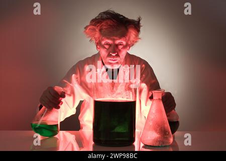 Un vecchio pazzo chimico che prepara un esperimento chimico con alcuni liquidi Foto Stock