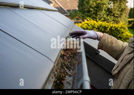 Uomo che pulisce il gocciolatoio bloccato. Foto Stock