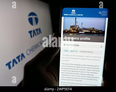 Persona che detiene lo smartphone con il sito web della società chimica indiana Tata Chemicals Limited davanti al logo. Messa a fuoco al centro del display del telefono. Foto Stock