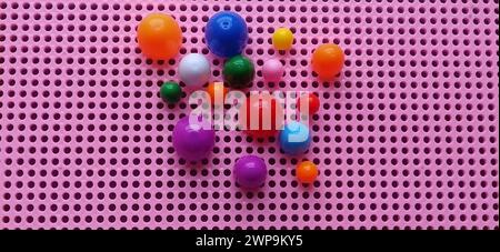 Gioco da tavolo - un mosaico per lo sviluppo delle capacità mentali e creative del bambino. Scatola di plastica rosa con fori. A sinistra, chip multicolore Foto Stock