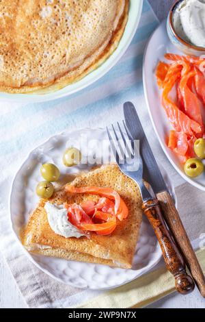 Pancake con gravlax, formaggio fresco e olive. Un piatto tradizionale per Maslenitsa o Carnevale. Foto Stock