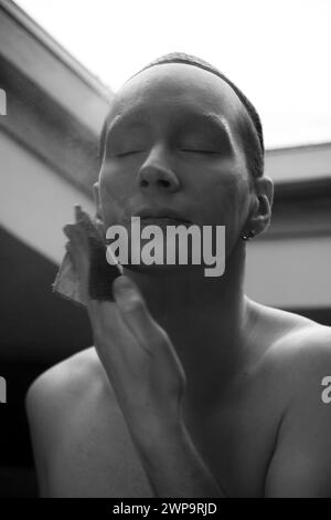 Un uomo che mette il trucco sul viso, gli occhi chiusi, la fotografia in bianco e nero, molta polvere Foto Stock