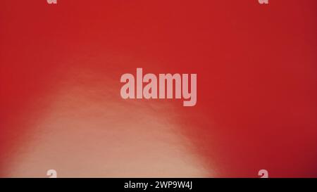 Sfondo rosso scuro morbido. Carta lucida, primo piano. Faretto illuminato in basso a sinistra. Foto Stock
