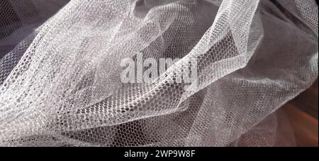 tessuto a rete sottile bianco. Tessuto per veli, tende, zanzariere, tulle e altri prodotti dell'industria leggera. Tulle sintetico increspato. Foto Stock