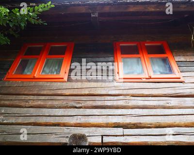 Finestre di Etno con una cornice di legno rossa. Esterno di una casa d'epoca. Complesso architettonico Stanisici. Cabina di legno. Edificio di Izba in un'area rurale boscosa sul Foto Stock