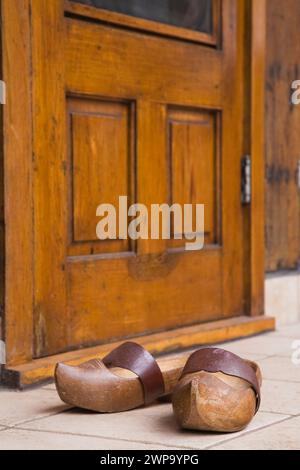 Un paio di vecchi zoccoli con cinturino marrone in pelle davanti alla porta d'ingresso posteriore sulla vecchia cabina in legno ricostruita. Foto Stock