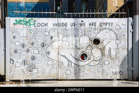 LONDRA, INGHILTERRA, Regno Unito - 4 MAGGIO 2014: Graffiti in bianco e nero che rappresentano la vita moderna (creati dal MIIIO) sul cancello nella zona di Brick Lane. Arte urbana Foto Stock