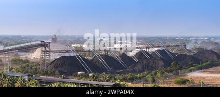 Puerto Quetzal, Guatemala - 19 gennaio 2024: Vista panoramica di grandi cumuli di carbone immagazzinati nel porto costiero della città Foto Stock