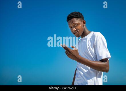 Un adolescente musulmano alla moda guarda in basso la macchina fotografica sulla spiaggia di Jambiani, Zanzibar, Tanzania Foto Stock