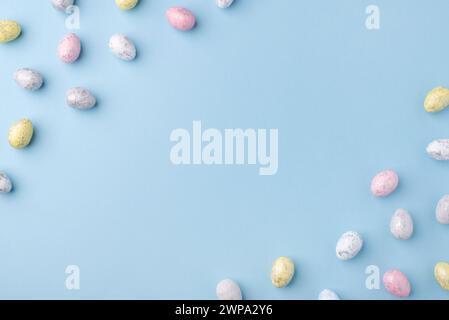 Sfondo natalizio di Pasqua. Uova di Pasqua multicolore su un tavolo blu. Scheda con spazio per il testo. Vista dall'alto. Foto Stock