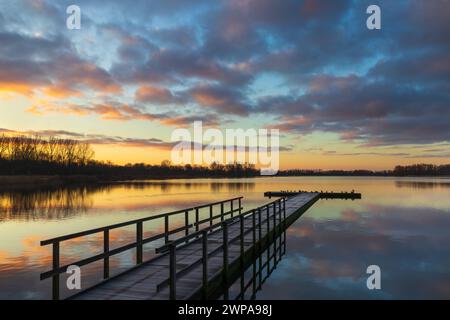 Molo nell'area ricreativa di Geestmerambacht (Paesi Bassi) sotto un cielo colorato all'alba. Una splendida alba con poche nuvole nel cielo. Foto Stock