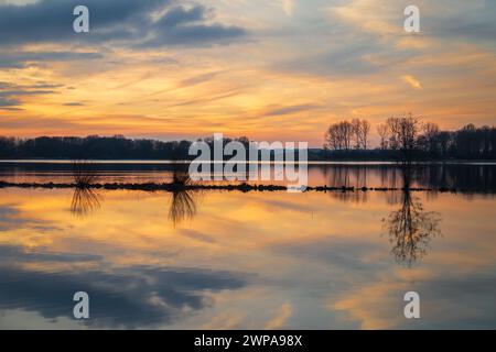 Il colorato tramonto si riflette nel lago nell'area ricreativa di Geestmerambacht. È privo di vento, facendo sì che l'acqua del lago funga da specchio. Foto Stock