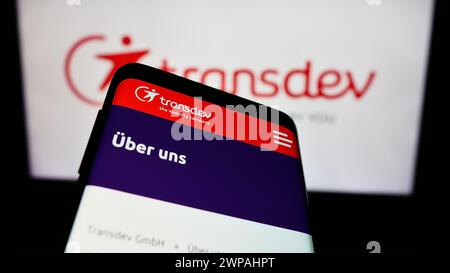 Telefono cellulare con sito web della società di trasporti pubblici tedesca Transdev GmbH davanti al logo aziendale. Mettere a fuoco in alto a sinistra sul display del telefono. Foto Stock