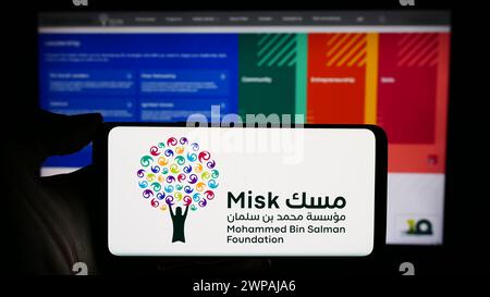 Persona che detiene un cellulare con il logo dell'organizzazione saudita Misk Foundation davanti alla pagina web. Mettere a fuoco il display del telefono. Foto Stock