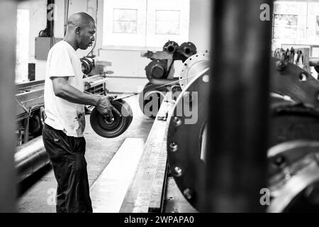 Uomo circondato da più motociclette in un garage di fabbrica Foto Stock