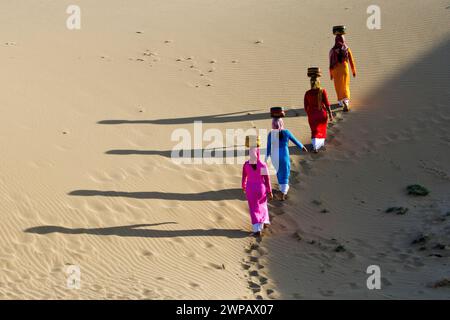 Donne che trasportano cesti, camminano tra le dune di sabbia vicino a Phan Rang, nel Vietnam centrale Foto Stock