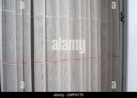 Tende bianche in cotone grosso o lino fatte di fili sottili. Semplice e compatto appartamento interno economico. Decorazione della finestra in camera. Rosso Foto Stock