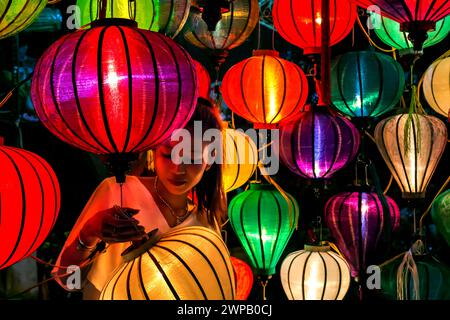 Una giovane donna che produce lanterne tradizionali in un negozio nell'antica città di Hoi An, sito patrimonio dell'umanità dell'UNESCO, in Vietnam Foto Stock