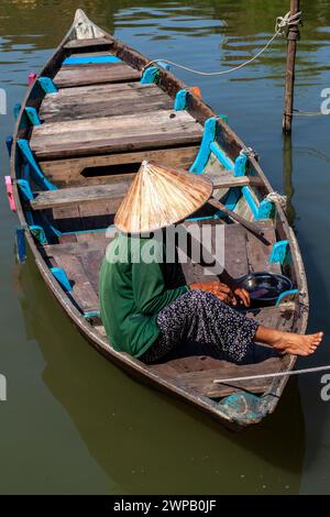 Hoi An, Vietnam; Una donna che si rilassa nella sua barca di legno. Foto Stock