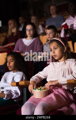 Presteen ragazza con afroamericano amico guardare film al cinema Foto Stock