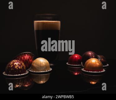 Caffè nero grande in una tazza di vetro a doppia parete con cialde colorate in schiuma Foto Stock