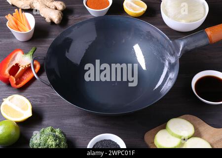 Wok vuoto circondato da ingredienti su un tavolo di legno grigio scuro Foto Stock