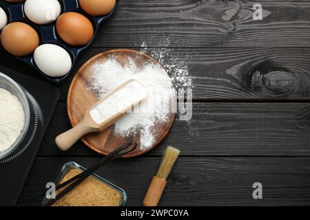 Composizione piatta con lievito in polvere e prodotti su un tavolo di legno nero. Spazio per il testo Foto Stock