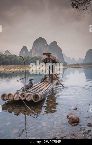 Navigando tranquillamente attraverso un fiume, i pescatori di cormorani di Guilin partirono sul fiume li durante la mattina presto. Foto Stock