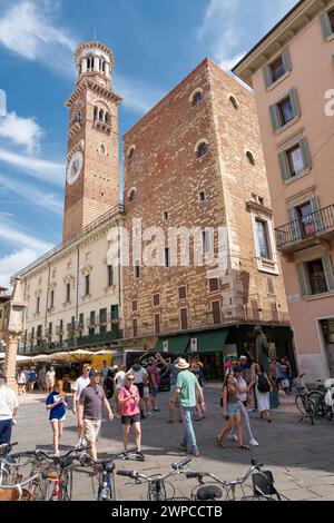 Turisti in Piazza delle Erbe con il campanile della Torre dei Lamberti nel centro storico di Verona in Italia Foto Stock