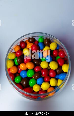 Caramelle dolci colorate in piatto di legno su sfondo nero, vista dall'alto Foto Stock