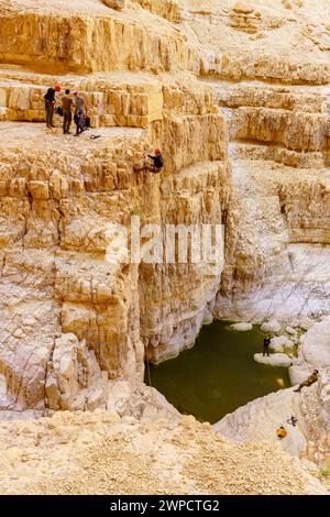 Masada, Israele - 19 gennaio 2024: Vista del paesaggio della valle desertica di Rahaf, con pozzanghere invernali e visitatori che praticano la discesa. Mar morto c Foto Stock