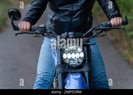 Cavalcare all'orizzonte. Primo piano dell'uomo motociclistico con la giacca nera. Persona sconosciuta dietro il manubrio. Lato anteriore della moto, Foto Stock