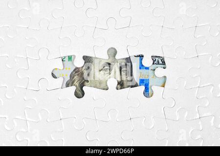 Lo sfondo del puzzle rivela scorci di elementi di banconote da cento dollari attraverso i pezzi mancanti. Ricchezza, strategia e concetto correlato alle opportunità. Foto Stock