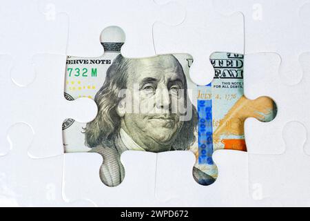 Sfondo puzzle con pezzi mancanti, rivelando elementi di una banconota da cento dollari. Opportunità finanziarie, strategia, prosperità, investimenti e fi Foto Stock
