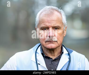 Ritratto di un medico anziano che guarda seriamente nella fotocamera. Foto Stock