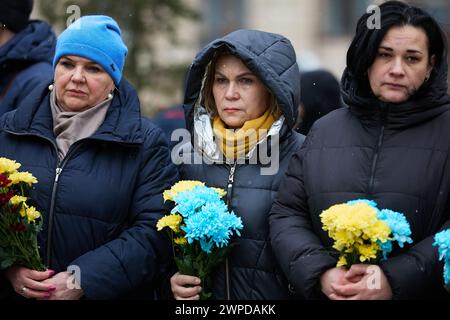 Tristi donne ucraine con fiori funebri in mano durante una cerimonia nel giorno degli Eroi dei cento celesti. Kiev - 20 febbraio 2024 Foto Stock