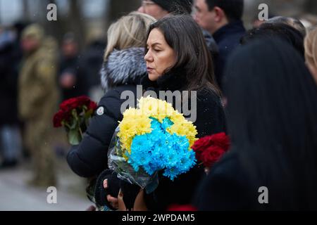 La donna Ucraina tiene un bouquet funebre di fiori blu e gialli in una cerimonia nel giorno degli Eroi dei cento celesti. Kiev - 20 febbraio 2024 Foto Stock