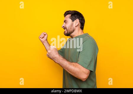 Foto ritratto di bel giovane maschio alzare pugni che combattono reazione irritata vestito elegante indumento cachi isolato su sfondo giallo Foto Stock