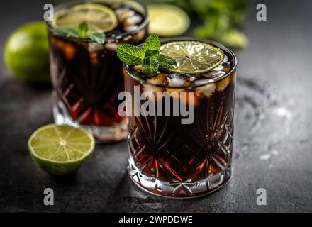 Cocktail alcolico tropicale Cuba Libre composto da rum bianco, cola, cubetti di ghiaccio, lime e menta. Foto Stock